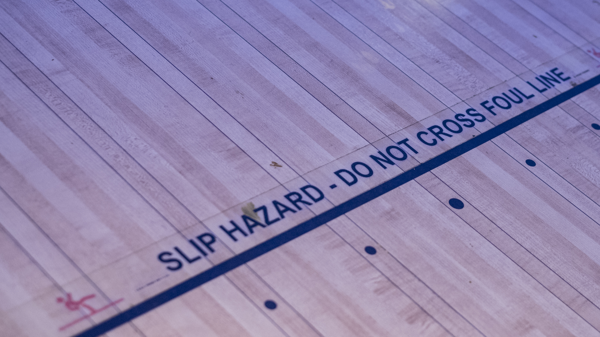 Detalj av bowling-banens parkett-gulv ved foul-linjen — slitt og levd-i