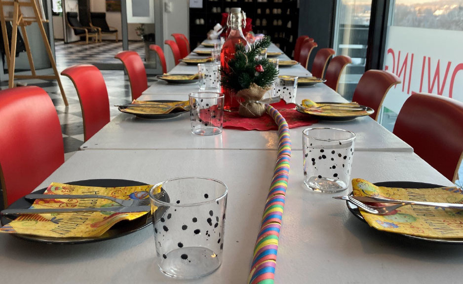 Langbord dekket til barnebursdag — gule servietter, sorte tallerkener, rosa bord-løper